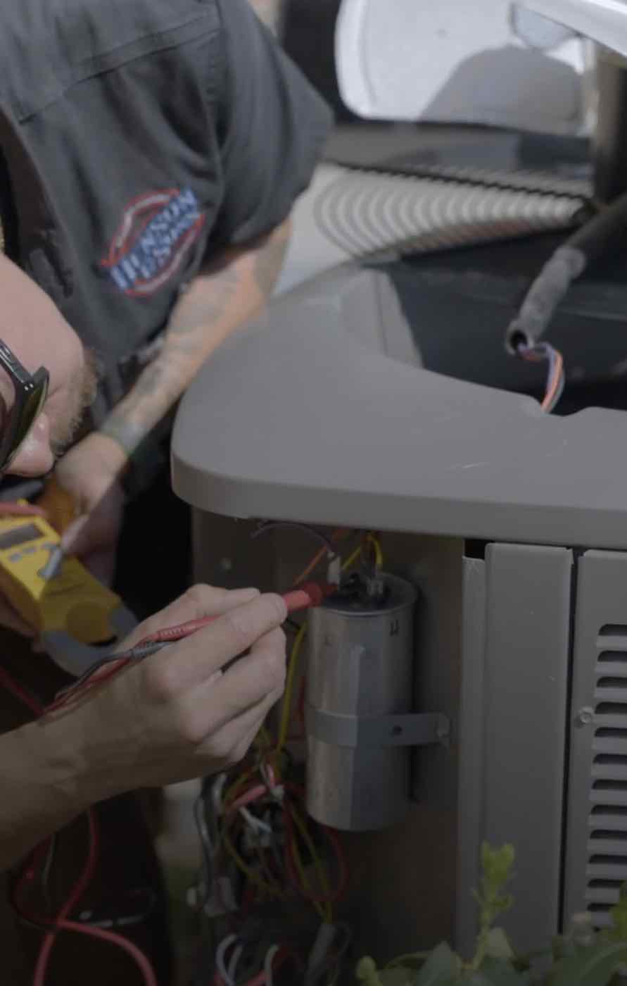 A technician working on an AC unit's wiring.